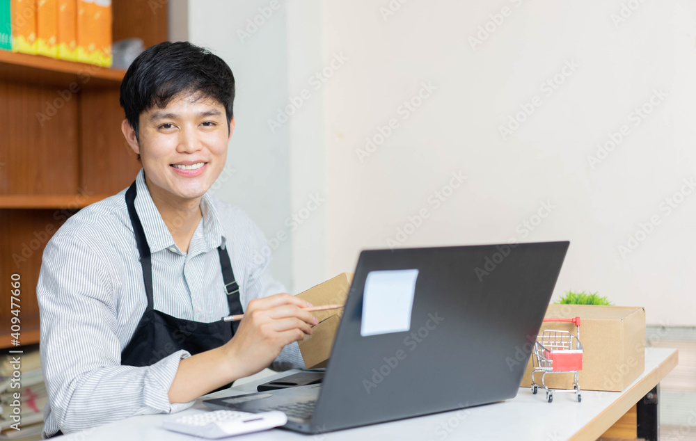 close up young business owner sitting at home office on the table while writing detail of customer on boxes to delivery for SME and startup concept close up young business owner sitting at home office on the table while writing detail of customer on boxes to delivery for SME and startup concept