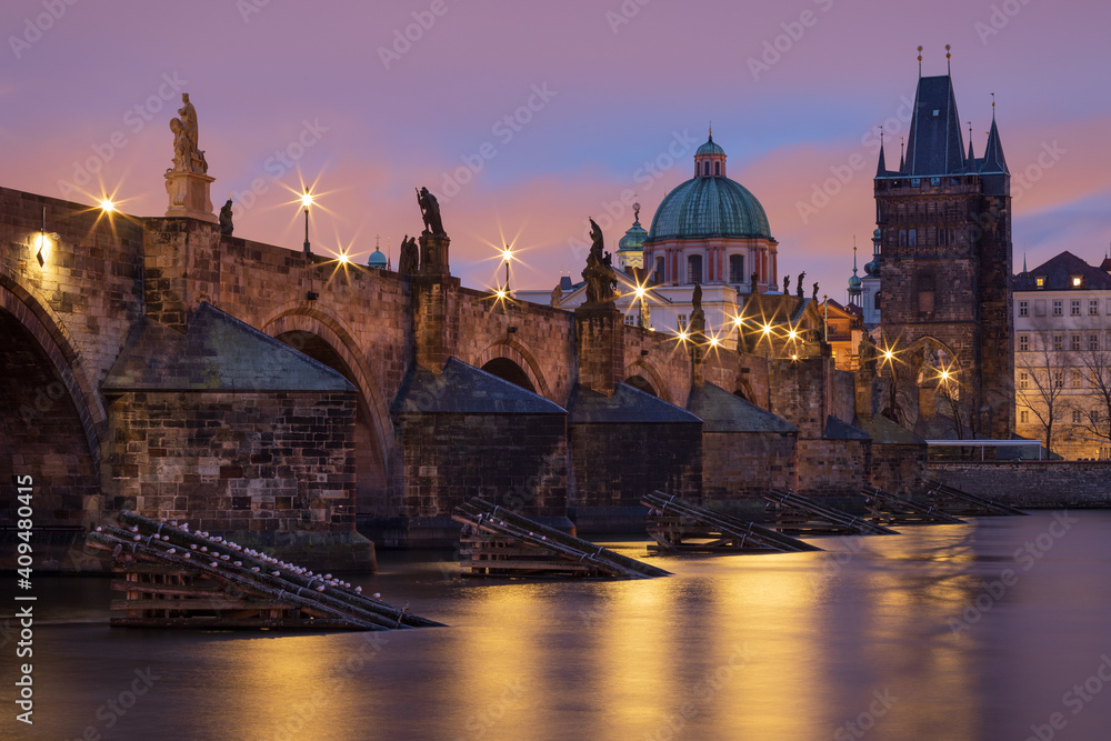 Naklejka premium View of illuminated historic Charles bridge and Vltava river in Prague, Czech Republic at twilight. Long exposure shot and star effect on street lamps