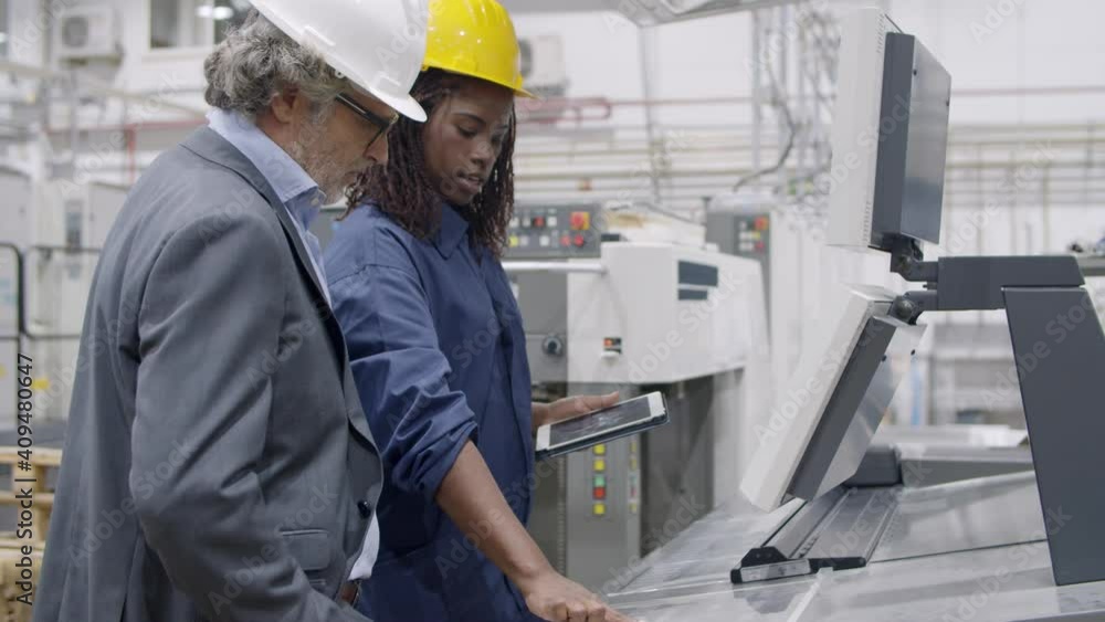 Black female factory engineer showing new machines control panel to senior factory owner or investor. Production process or machinery concept Black female factory engineer showing new machines control panel to senior factory owner or investor. Production process or machinery concept