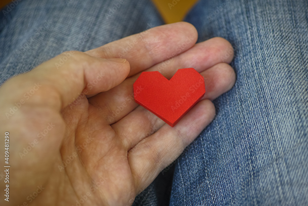 Man holding a red origami heart in his palm. Close up. Man holding a red origami heart in his palm. Close up.