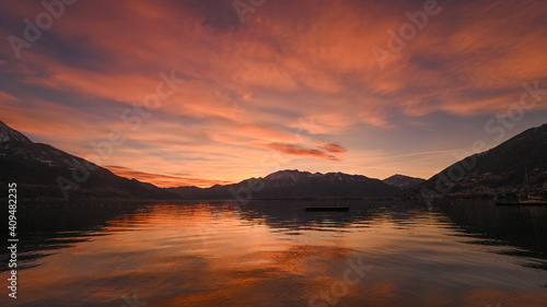 Favoloso tramonto sul lago, con nuvole arancioni e rosse che si riflettono nell'acqua del lago © fotonaturali