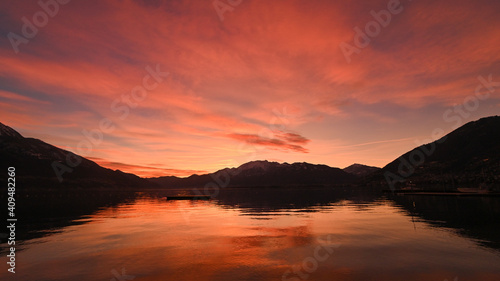 Favoloso tramonto sul lago  con nuvole arancioni e rosse che si riflettono nell acqua del lago