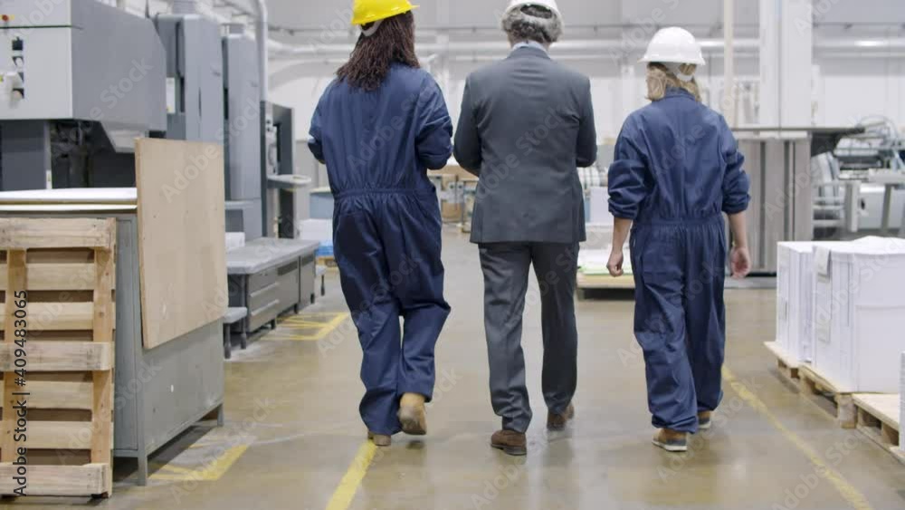 Team of senior engineer and two diverse female workers in hardhats walking on plant floor and discussing equipment and machinery work process. Industrial occupation concept Team of senior engineer and two diverse female workers in hardhats walking on plant floor and discussing equipment and machinery work process. Industrial occupation concept