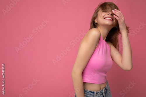 Photo of attractive cute happy emotional young woman poising isolated on background wall with free space wearing trendy casual clothes