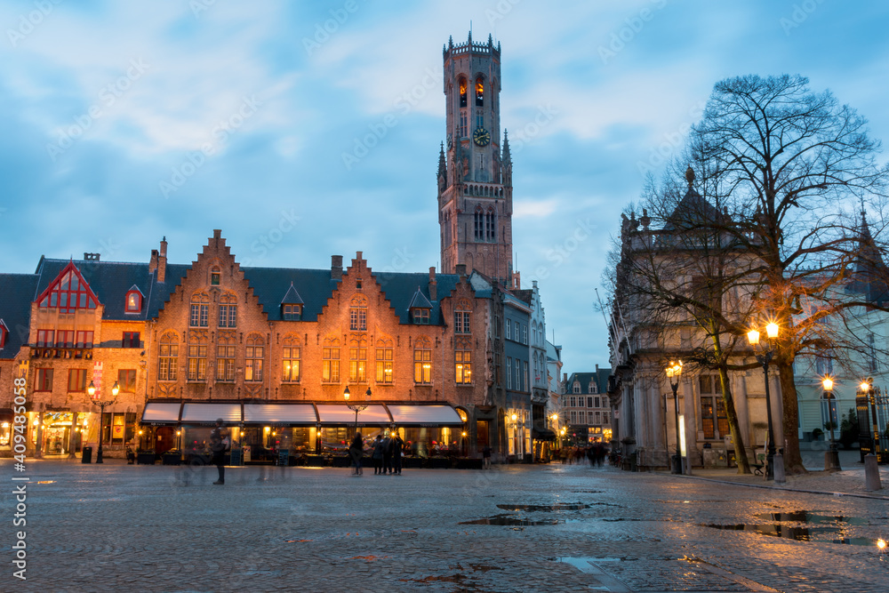 Burg Square at sunset with puddles after the rain. Bell Tower in the background. Bruges, Belgium.