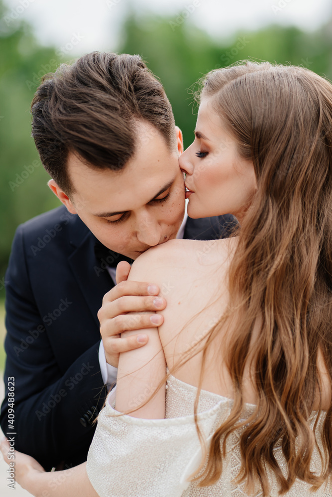 beautiful, gentle and happy bride and groom. man gently kisses woman's shoulder beautiful, gentle and happy bride and groom. man gently kisses woman's shoulder