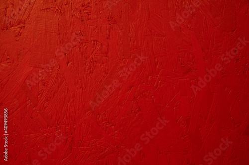 Bright red wooden background wall. Painted OSB board texture. Small budget construction material.OSB or chipboard is made from wood waste products - wood chips, wood shavings, sometimes even sawdust.