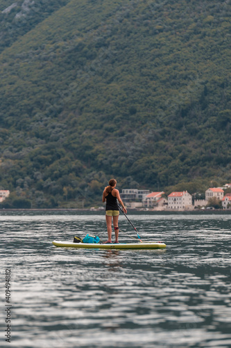 Young woman on SUP stand up paddle board in Kotor bay (Boka Kotorska), Montenegro, Europe