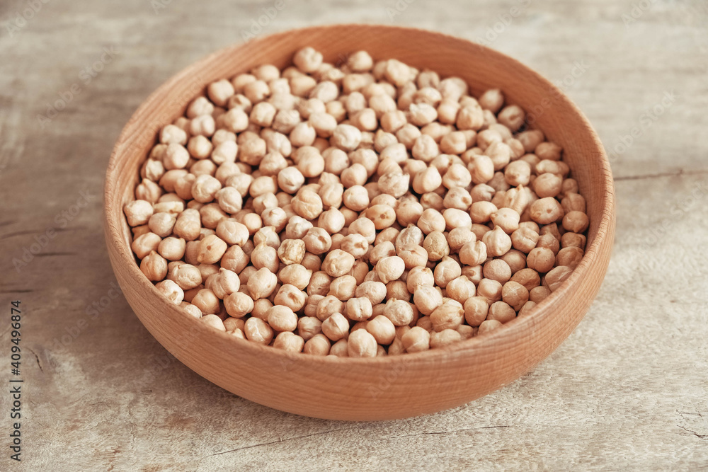 Raw chickpeas in a wooden plate on a wooden background. Top view. Copy, empty space for text Raw chickpeas in a wooden plate on a wooden background. Top view. Copy, empty space for text