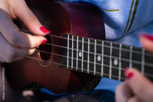 closeup of young man playing ukulele at the river in sunny field and water cordoba argentina