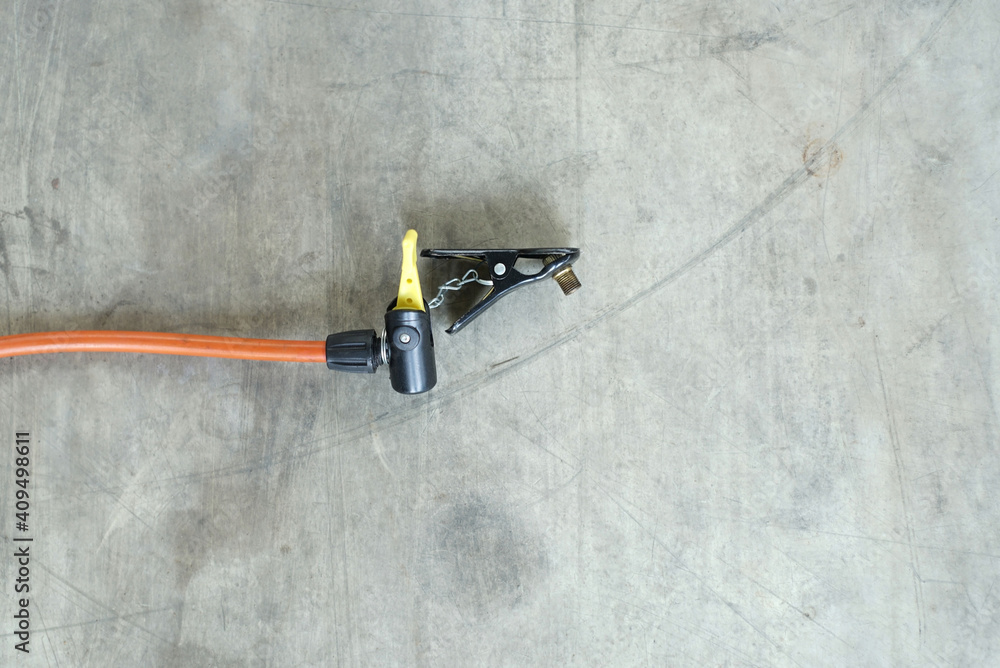 Close-Up a cables with a Bicycle inflator head on the cements ground. Close-Up a cables with a Bicycle inflator head on the cements ground.