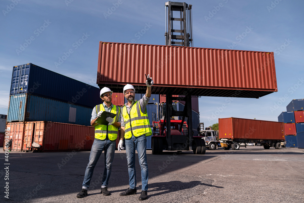 Logistics engineer and inspector working and discuss in shipping container in commercial transport port