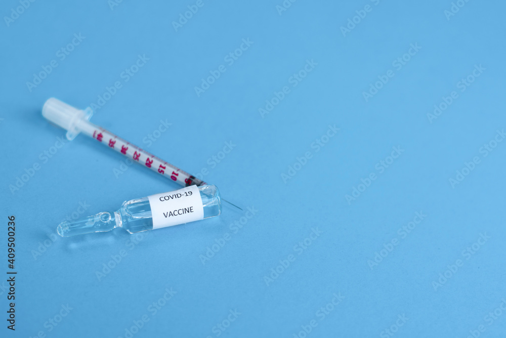 Obraz premium Glass vaccine and syringe for vaccination against the COVID-19, SARS-CoV-2 coronavirus pandemic on blue background