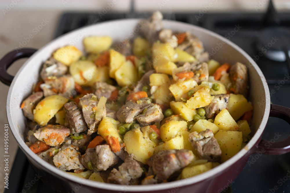 Meat stewed with potatoes, carrots, vegetables and spices in a pan. Process of cooking dish in a kitchen. Selective focus with copy space Meat stewed with potatoes, carrots, vegetables and spices in a pan. Process of cooking dish in a kitchen. Selective focus with copy space