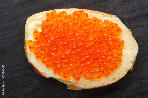 Canapes with butter and red caviar on a black background.