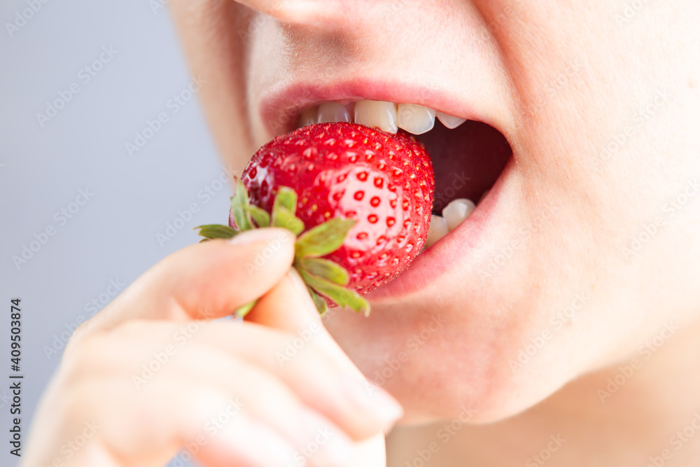 Closeup of woman mouth eats a ripe strawberry, the concept of a healthy lifestyle with organic products and vitamins. Attractive caucasian female with a happy expression. Closeup of woman mouth eats a ripe strawberry, the concept of a healthy lifestyle with organic products and vitamins. Attractive caucasian female with a happy expression.