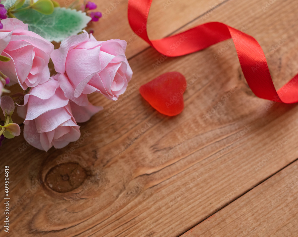 Pink roses on a dark wooden background with a red ribbon and a heart. Concept of Valentine's day. Copy space for text. Pink roses on a dark wooden background with a red ribbon and a heart. Concept of Valentine's day. Copy space for text.