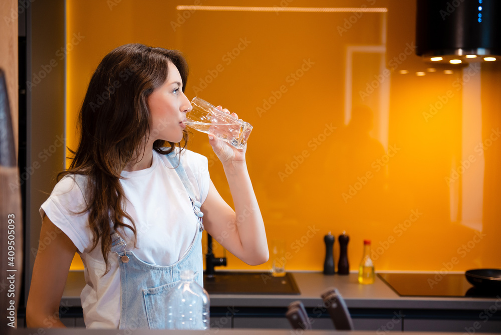 Attractive woman drinking water from glass on kitchen Attractive woman drinking water from glass on kitchen
