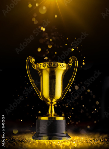 Golden trophy on black background in rays of light.