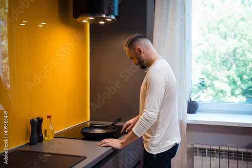 Side view of bearded man cooking on bright kitchen
