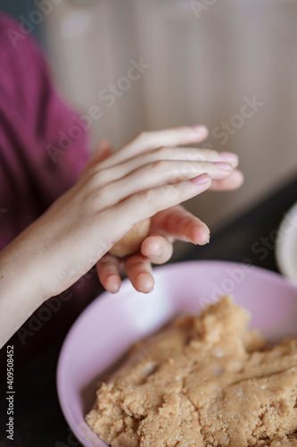 Child hands making sweet balls cookies called Potato of marzipan, biscuits, cocoa. Process of dessert cooking, wooden table with ingredients. Selective focus, copy space