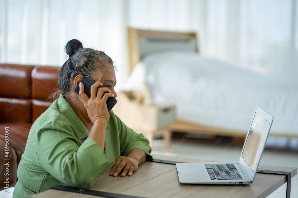 Asian senior retired business woman working at home with Laptop computer in new normal Asian senior retired business woman working at home with Laptop computer in new normal