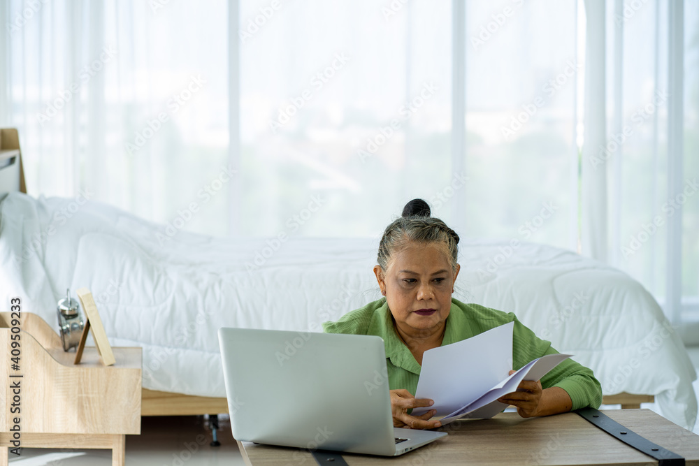 Asian senior retired business woman working at home with Laptop computer in new normal Asian senior retired business woman working at home with Laptop computer in new normal