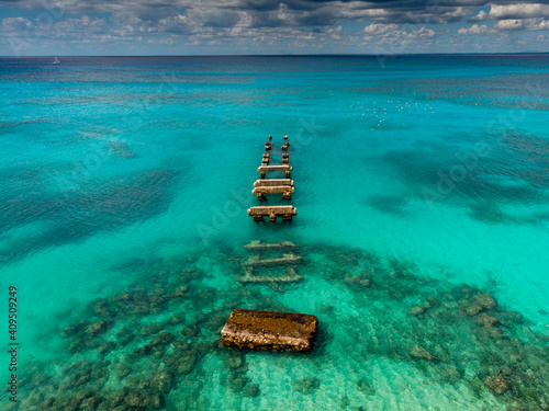 Aerial drone view of the old broken pier and blue water of Caribbean Sea with transparent coral bottom, Saona island, Dominican Republic