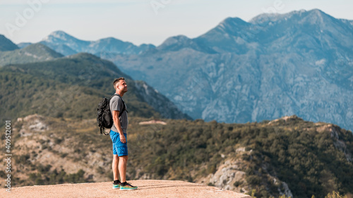 Young athletic traveler with a backpack stands on the top of the mountain at Kotor bay (Boka Kotorska), Montenegro, Europe