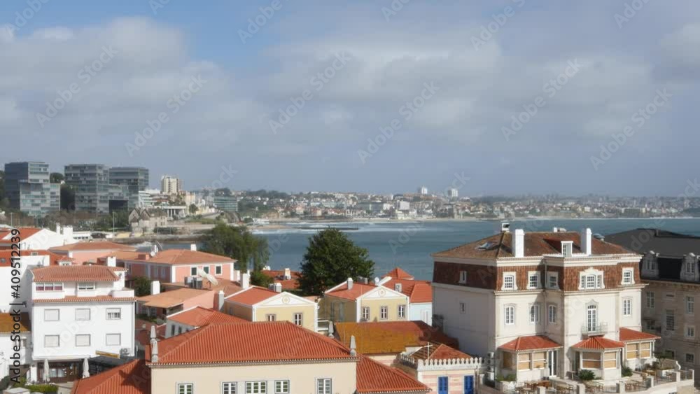 Waves crashing in Cascais and Estoril, Portugal with traditional Portuguese architecture on foreground Waves crashing in Cascais and Estoril, Portugal with traditional Portuguese architecture on foreground