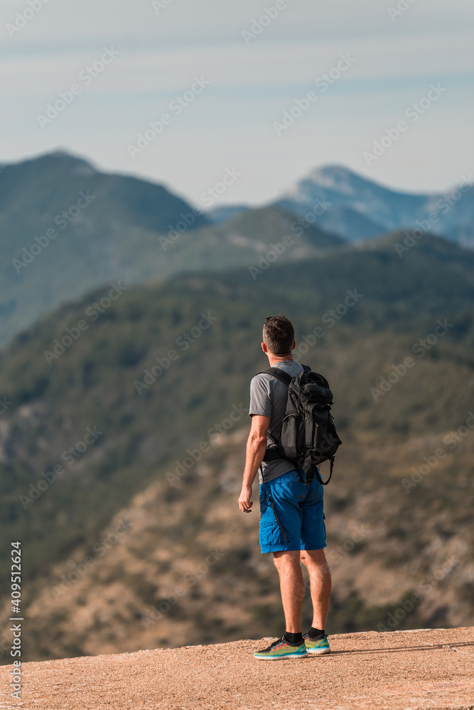 Young athletic traveler with a backpack stands on the top of the mountain Kotor bay (Boka Kotorska), Montenegro, Europe
