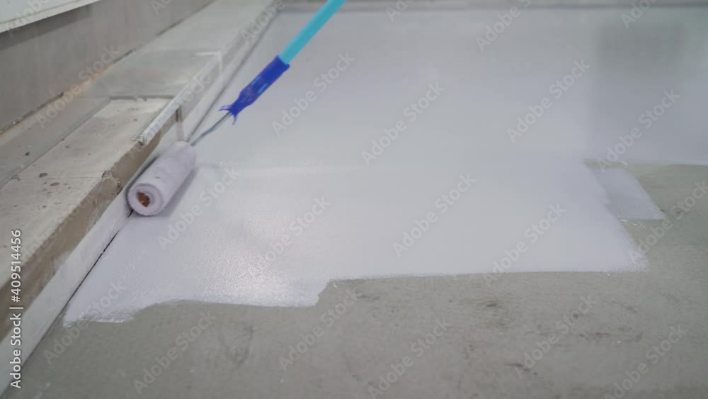 Application of white paint to the concrete floor. Primer for concrete