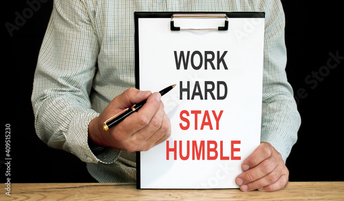 Photography Work hard stay humble word inscription on white card paper sheet in hands of a businessman