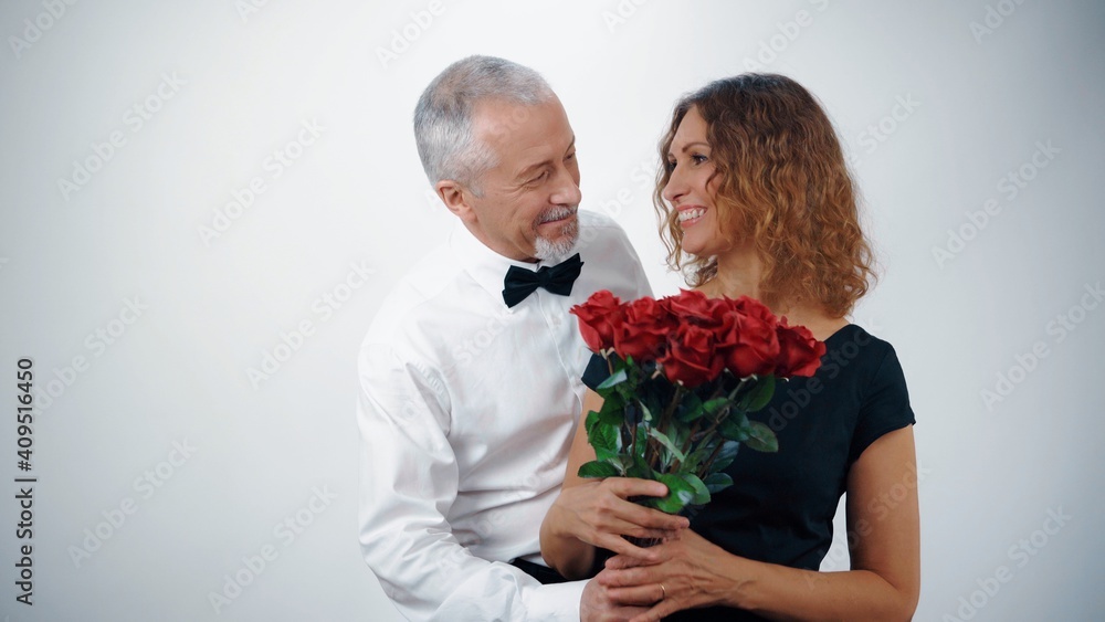 A loving elderly man gives his elderly wife red roses for the anniversary. A loving elderly man gives his elderly wife red roses for the anniversary.