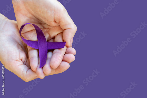 hands holding ribbon with purple bow. February Roxo, awareness month about Lupus, Fibromyalgia and Alzheimer. Space for text. photo