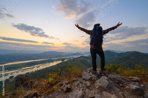 Rear view of man open arms standing on the cliff enjoying watch Mekong river at sunrise in Nong Khai, Thailand