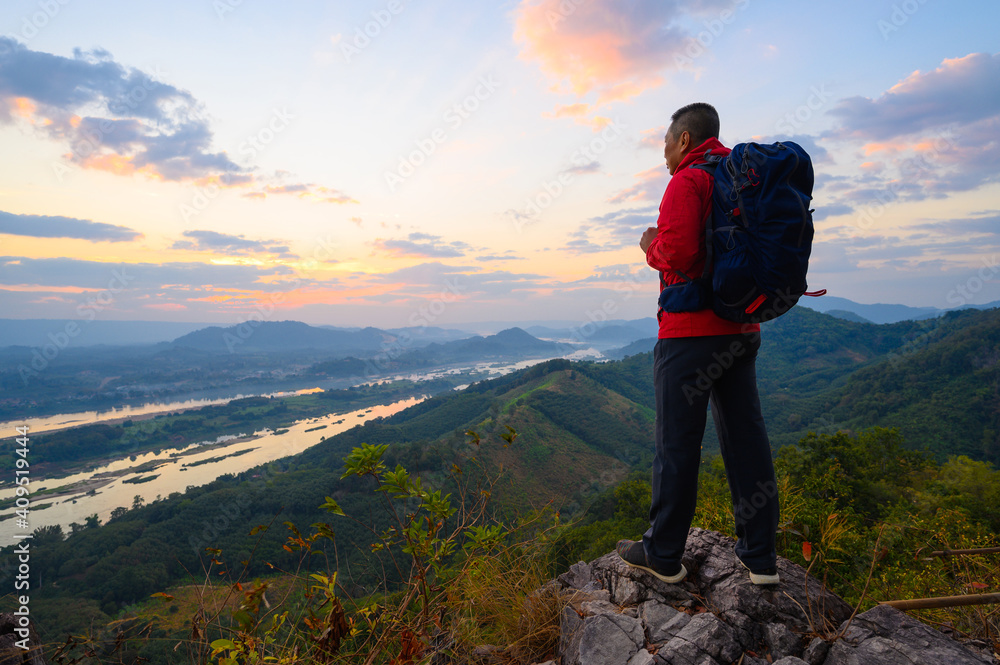 Senior man enjoys the view of cliff after hiked the hill to watch the sunrise over mekong river in morning at phu pha dak in nong khai, Thailand