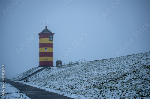 Foto Otto lighthouse in Pilsum in the snow with fog in winter