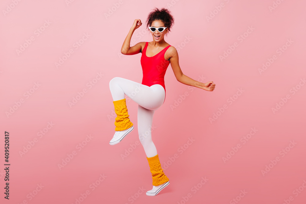 Stunning black girl dancing with smile on pink background. Gorgeous african woman doing aerobics. Stunning black girl dancing with smile on pink background. Gorgeous african woman doing aerobics.