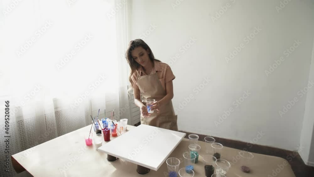 Young beatiful female artist woman prepares colors and drawing a picture of fluid art Young beatiful female artist woman prepares colors and drawing a picture of fluid art