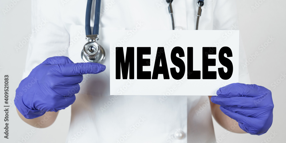 The doctor points his finger at a sign that says - MEASLES The doctor points his finger at a sign that says - MEASLES