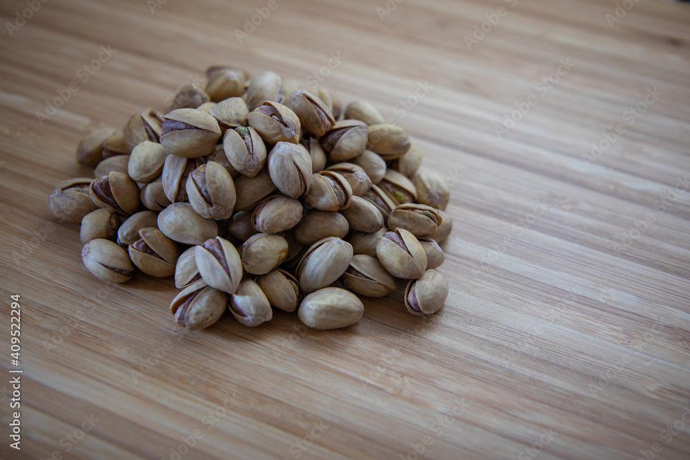 Pile of salted pistachios, standing on a wooden table. Pile of salted pistachios, standing on a wooden table.