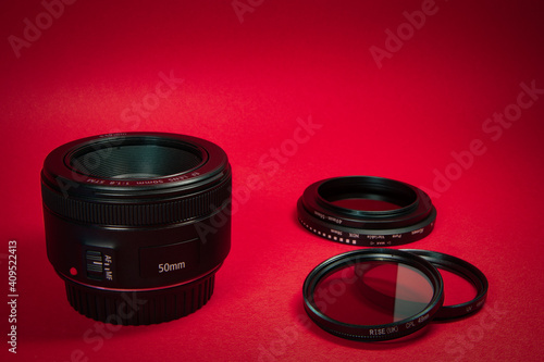 Close up 50 mm prime lens. polarized filter, a uv filter and a neutral density filter behind with a red background.