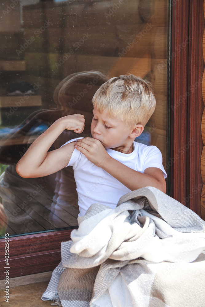 Fototapeta premium Cute boy sitting in a cozy blanket outdoors