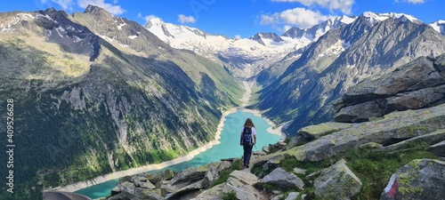 A girl hiking towards the Olperer hut with amazing views of Alpine lake Schlegeis in the valley Zillertal, Austrian Alps photo