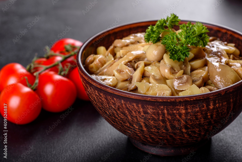 Fresh delicious spicy canned mushrooms with spices and herbs in ceramic dishes