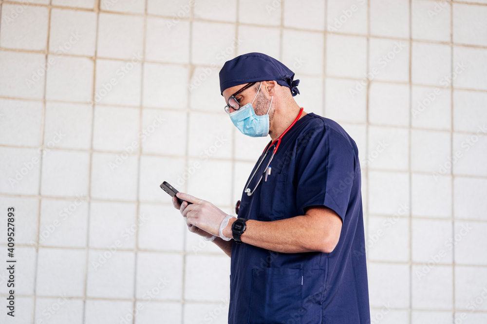 Doctor walking outside hospital using smart phone