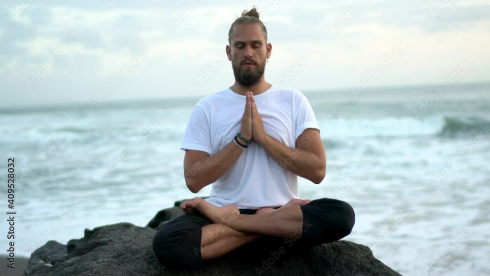 Young male sitting in lotus pose for search own mindfulness feel ocean and nature energy, Caucaisan man meditating in namaste concentrated on mantras Young male sitting in lotus pose for search own mindfulness feel ocean and nature energy, Caucaisan man meditating in namaste concentrated on mantras