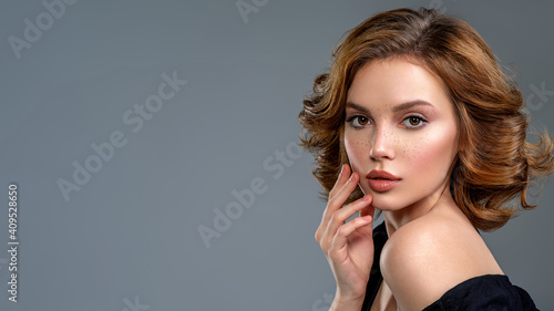 Woman with a  curly hair. Beautiful young woman with freckles on face.   Beautiful brown haired with stylish short hairstyle.  Closeup portrait of an attractive girl  with a brown makeup.