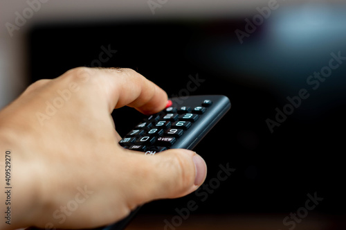 Fotografia Male hand holding a TV remote and trying to turn on the TV